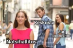 Mies (keskusta) on kävelyllä tyttöystävän (muu oppositio) kanssa, kääntyy katsomaan ohikulkevaa punamekkoista naista (natsihallitus).