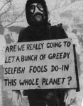 Man in gas mask carrying a sign: Are we really going to let a bunch of greedy selfish fools do-in this whole planet?