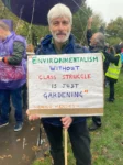 Man holding a sign: Environmentalism without class struggle is just gardening. -Chico Mendes